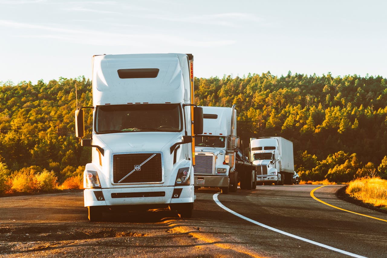 services-03 Three semi trucks driving on a highway through a forested landscape in Arizona.